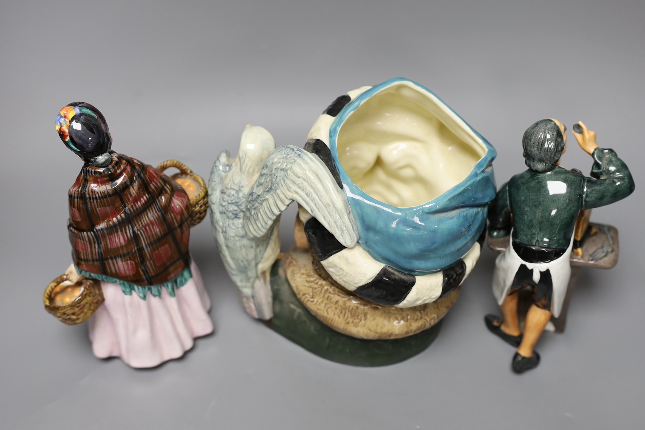 Two Royal Doulton figures, ‘The Clockmaker HN2279’ and ‘The Orange Lady HN1759’ together with a character jug ‘The Falconer D6533’